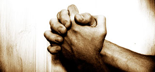 Prayer Request Form with hands clasped praying on a wooden table.